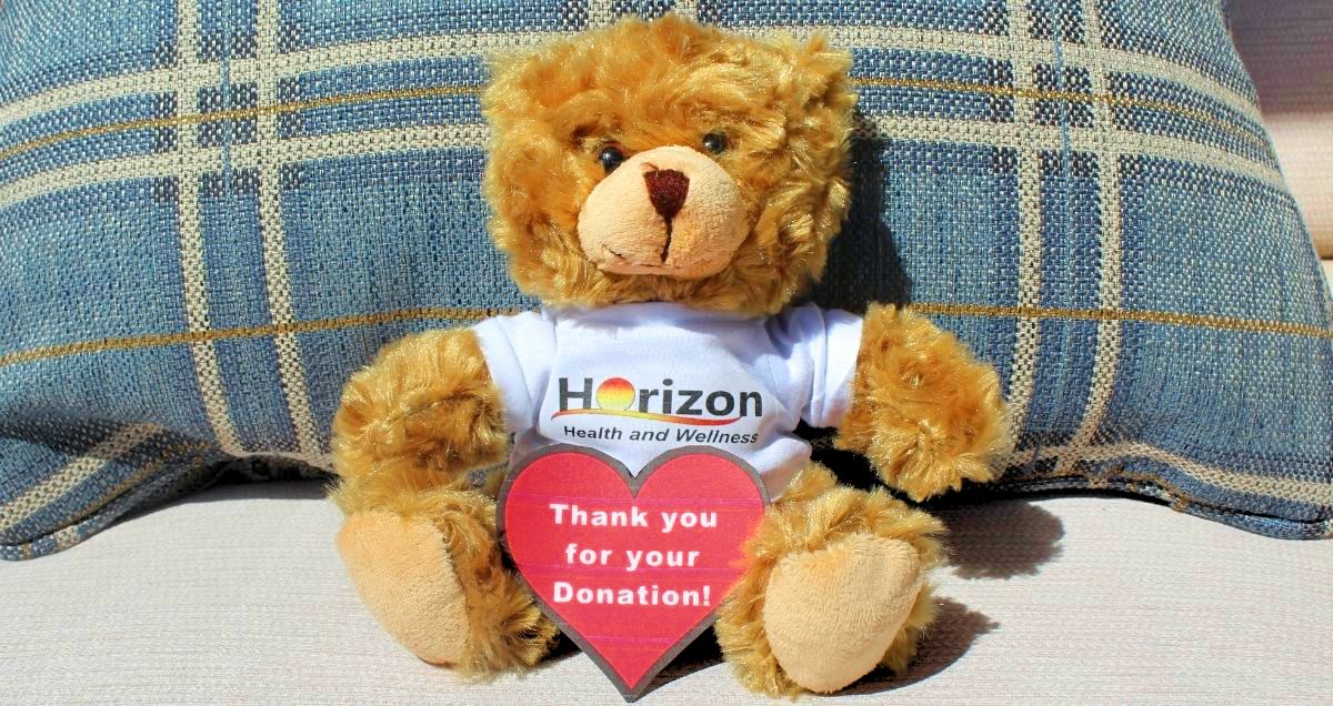 A brown, stuffed bear with a Horizon Health and Wellness shirt and a cardboard heart that says, "Thank you for your donation!"