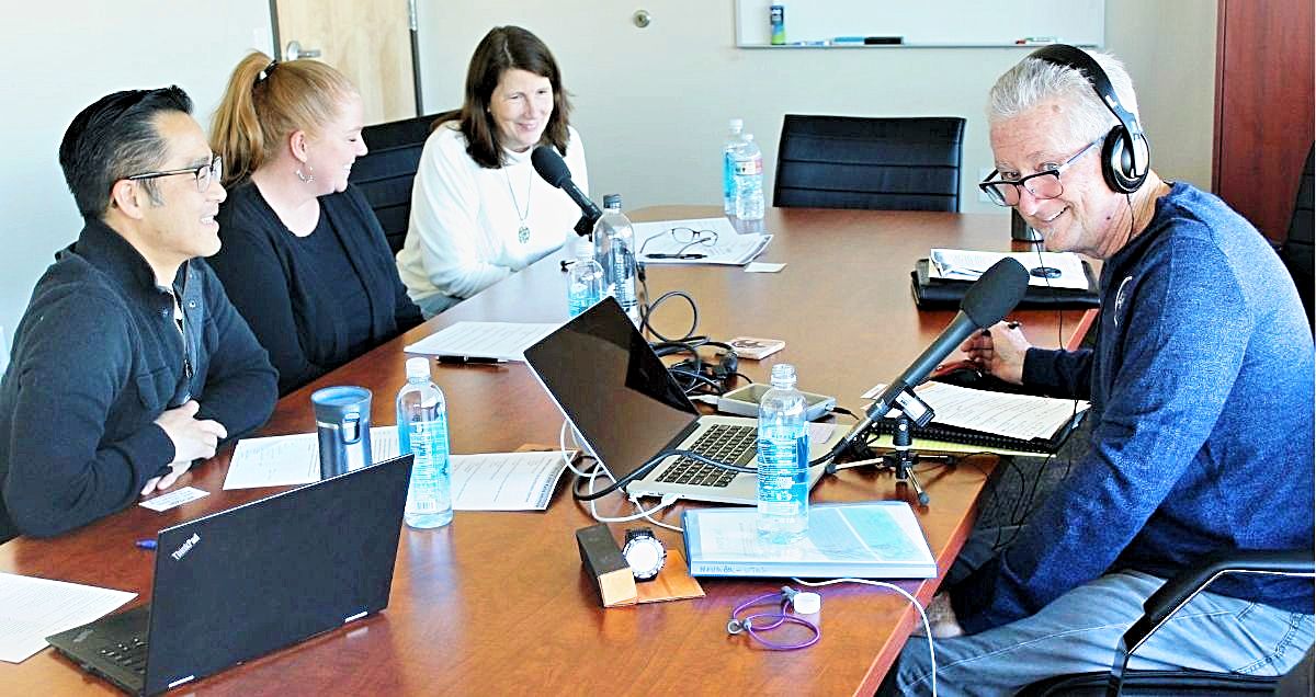 A radio interview in a conference room with three Horizon employees and the show host wearing headphones.